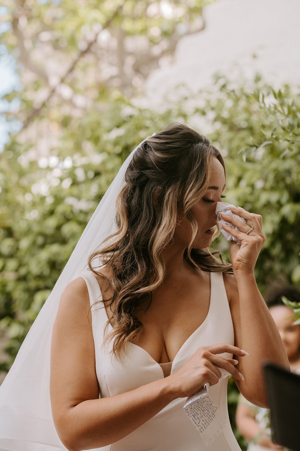 Emotional bride in white gown and veil wiping tears outdoors on her wedding day at Darlington House.