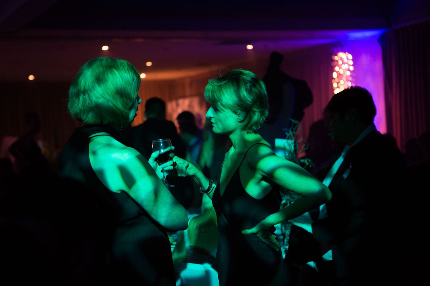 Candid photo of a guest talking to another guest in dramatic light at a charity event