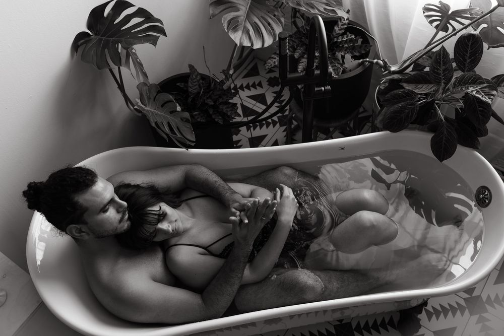 A monstera plant leaf casts dramatic shadows against a light colored wall in black and white photography.