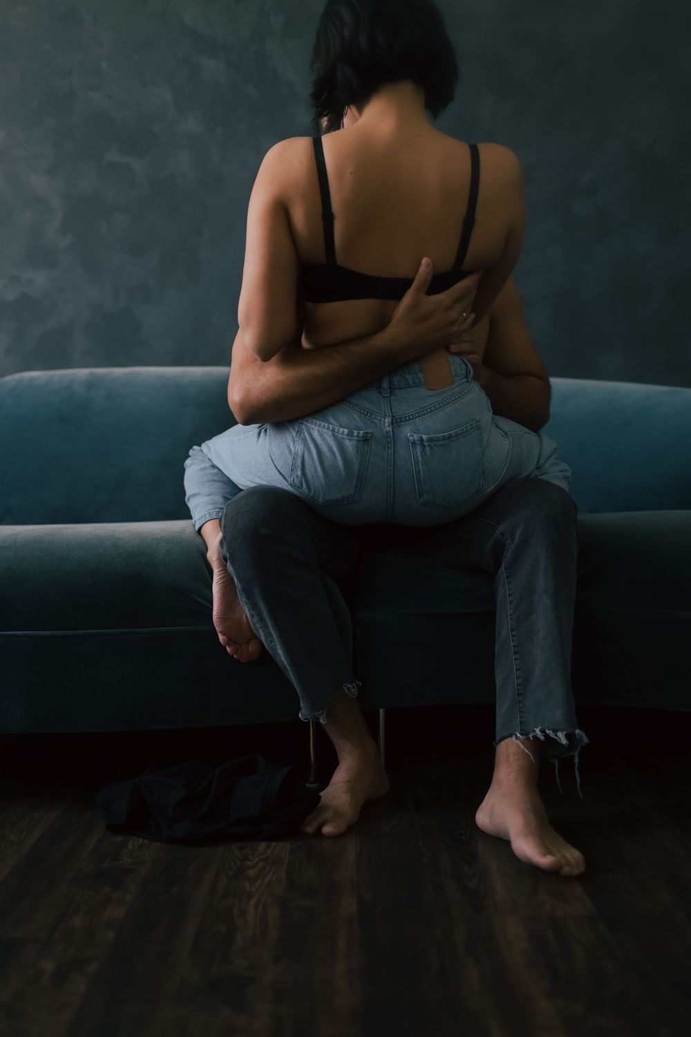 A series of moody photographs showing a person sitting on a dark couch in casual clothing against a textured wall.