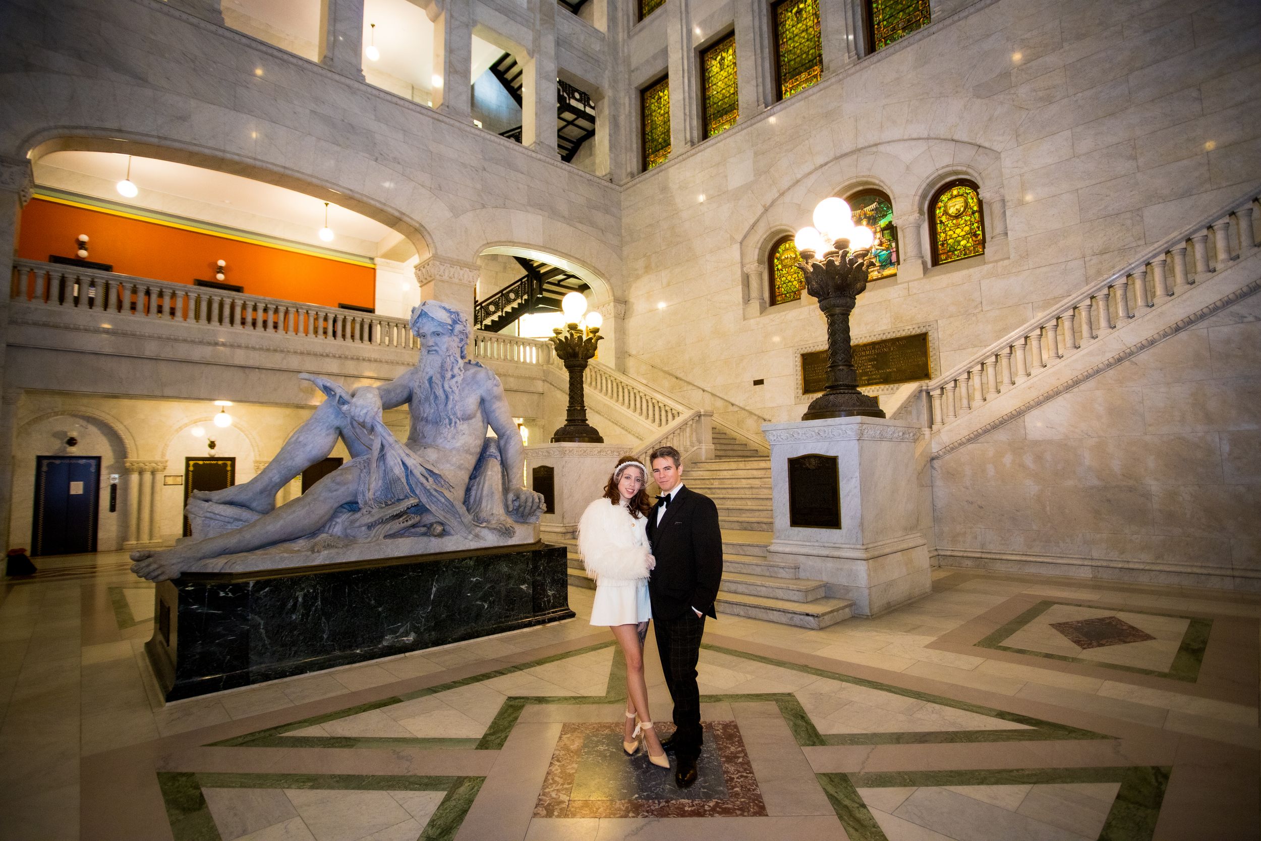 Elegant marble staircase in grand building interior with ornate architectural details and warm lighting.