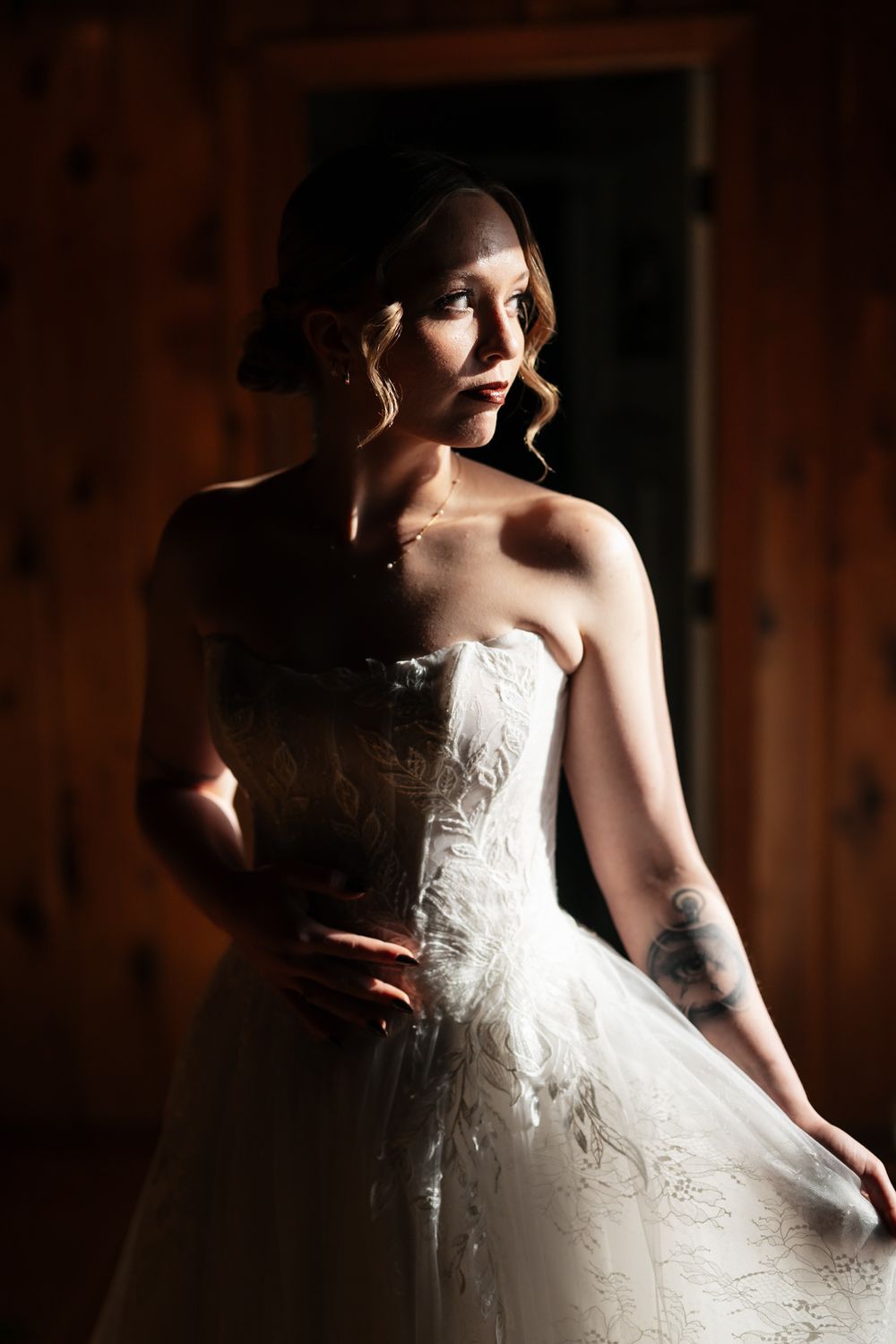 A bride in a white strapless wedding gown poses dramatically in moody lighting creating artistic silhouettes.