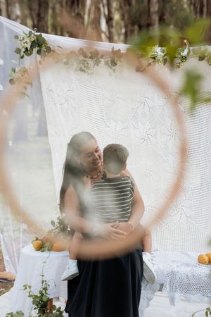 A romantic couple embraces in a dreamy setting with white lace curtains and delicate greenery decorations.
