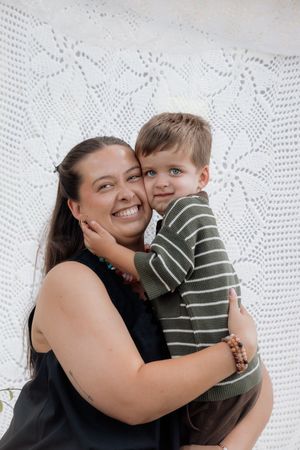 A joyful parent and child share loving embraces against a white lace backdrop in a series of candid moments.