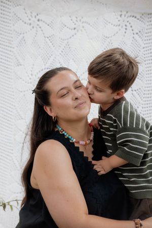 A tender moment captured against a white lace backdrop as a young child gives a sweet kiss.