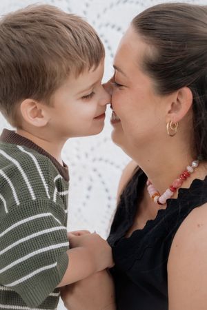 An affectionate close-up portrait showing a touching nose-to-nose moment against white lace background.