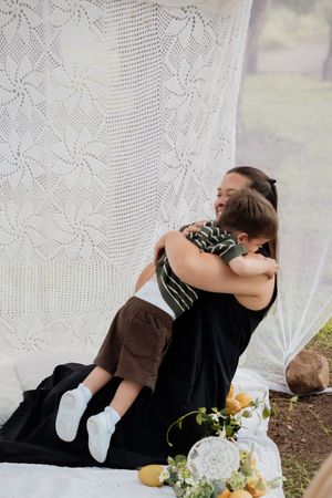 Sweet candid moments shared between two people with white lace curtains and floral decor.