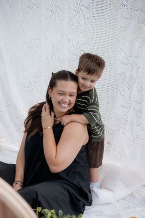 Natural light portrait showing genuine laughter and embraces on white backdrop.