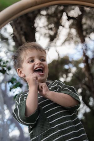 A candid portrait of pure childhood joy and laughter captured through a circular frame outdoors.
