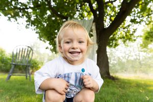 Children playing under green trees on a sunny summer day.