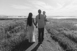 Silhouettes of people walking together on a grassy path during sunset.