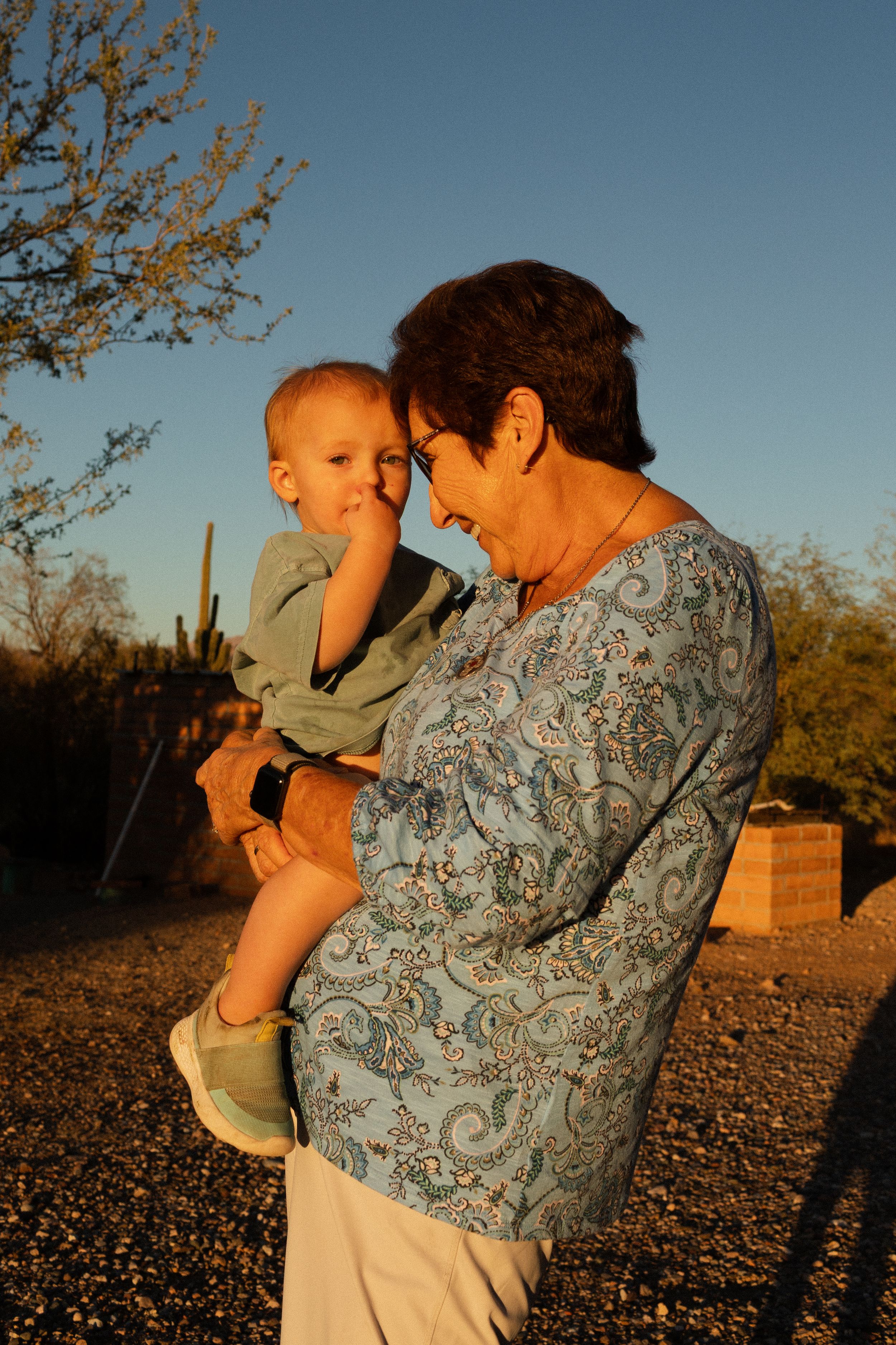 A tender moment captured at sunset in the desert with cacti in the background.