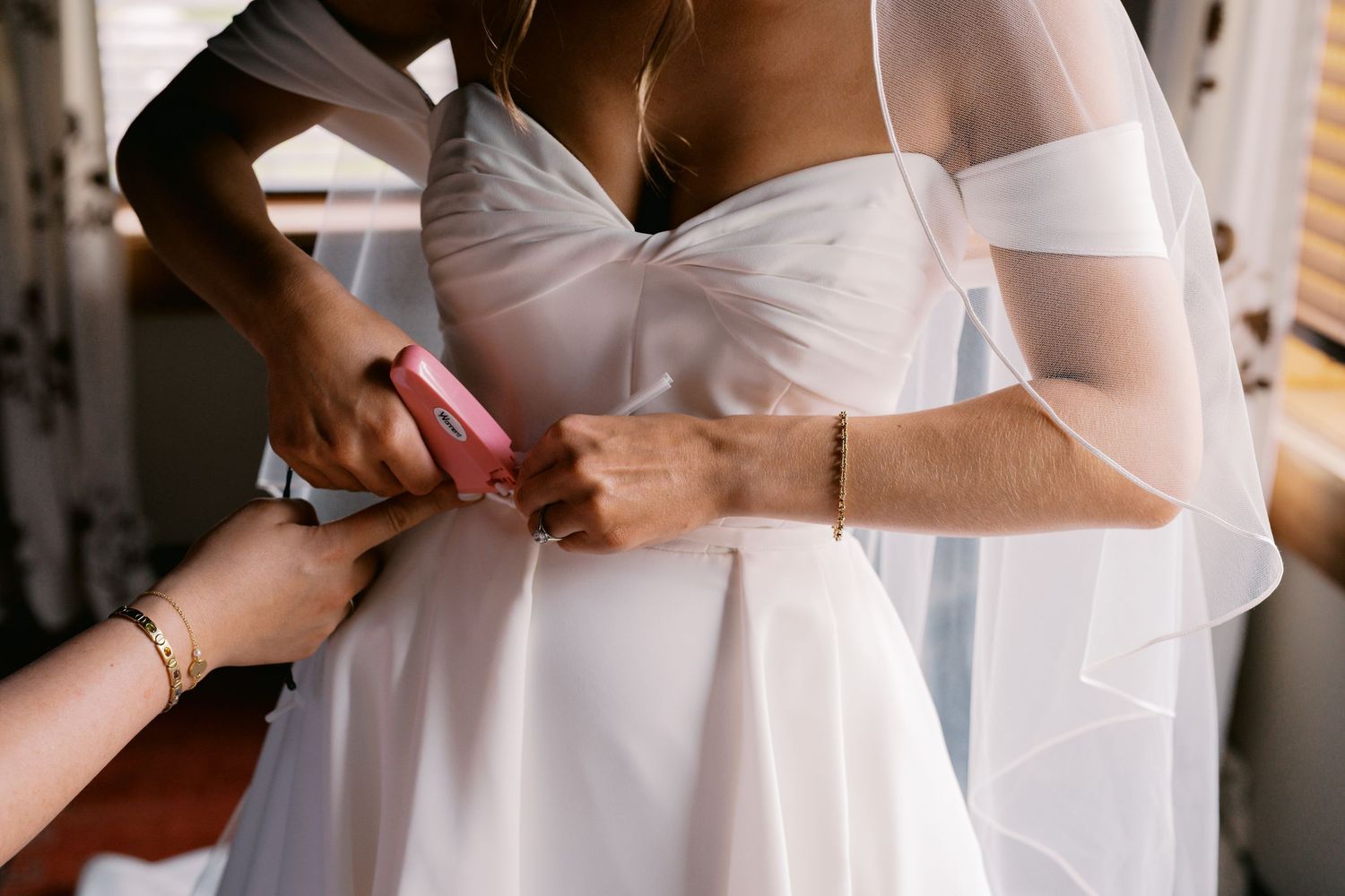 Close-up detail shots of a bride getting dressed in a white wedding gown with lace and buttons.