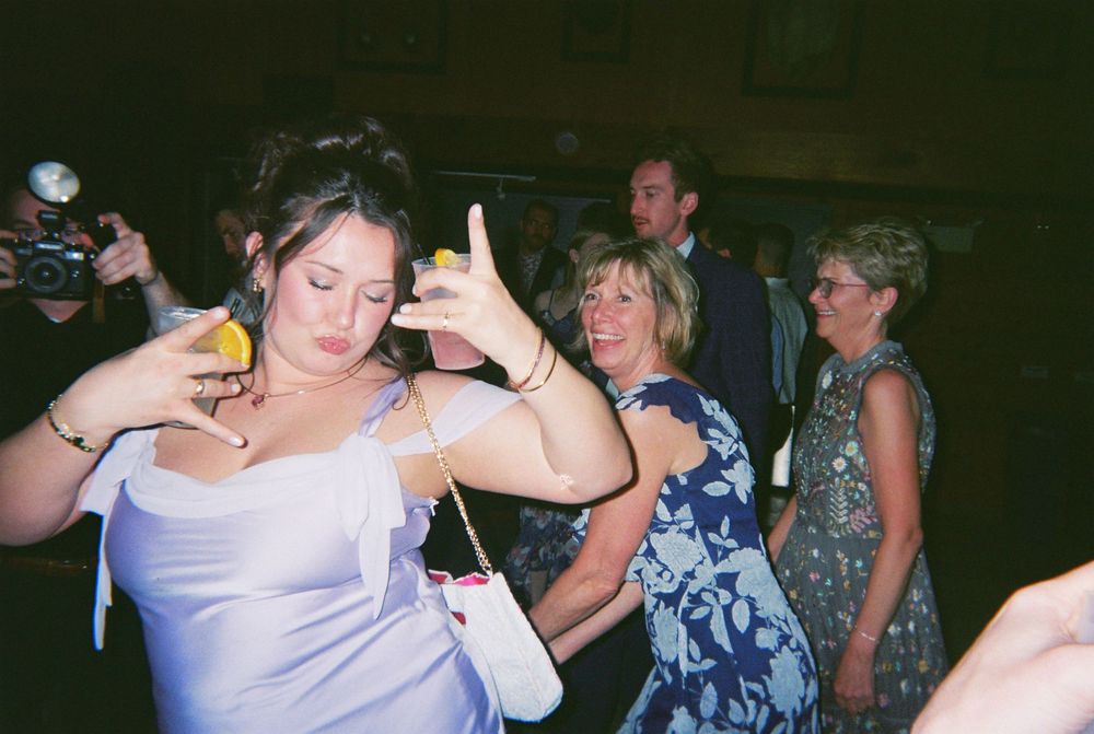 A group of people dancing and celebrating at a dimly lit party venue with blue lighting effects.
