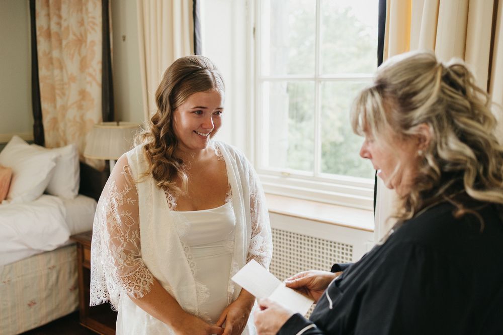 Wedding party members gather in a bright room with natural light streaming through windows.