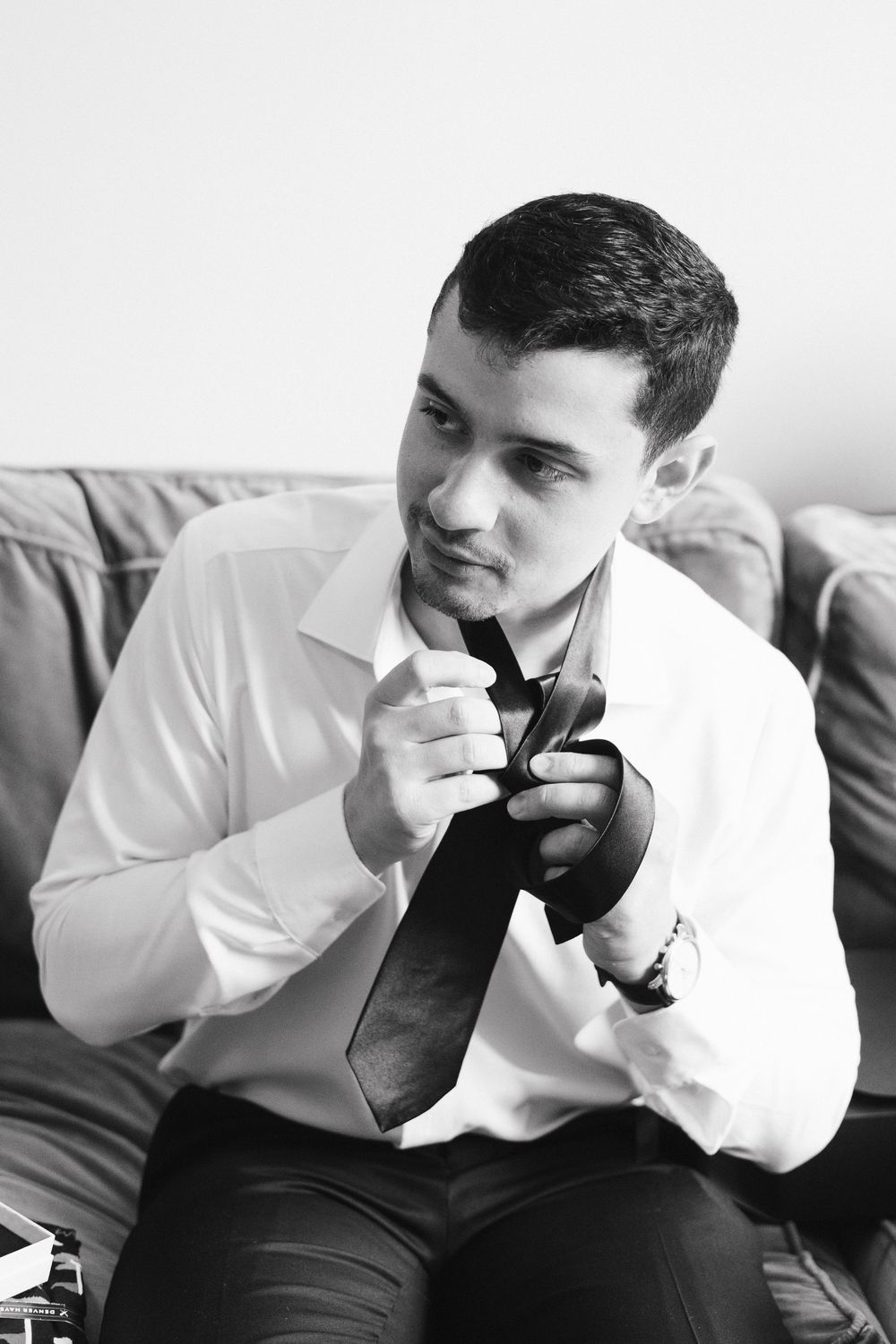 A sequence of black and white photos showing someone in a white dress shirt putting on a black bowtie.