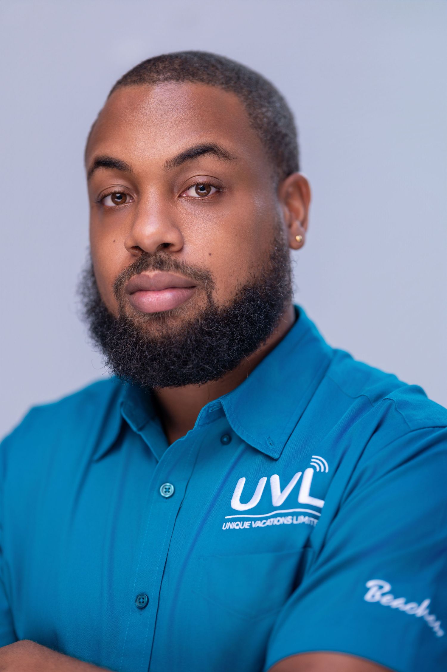 Professional headshot of someone wearing a bright blue polo shirt with embroidered company logo against light background.