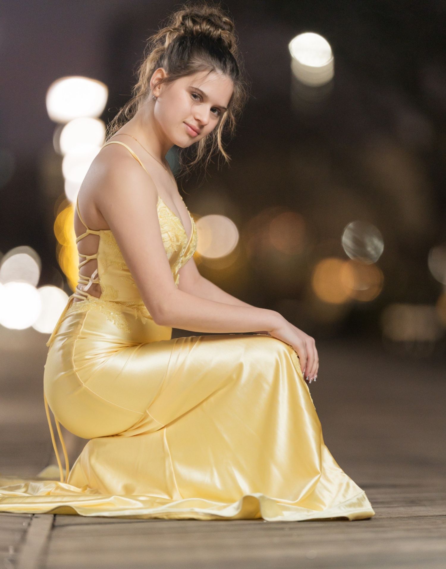 Back view of Ava in a yellow prom dress at night showing the lace-up back at the Wilmington Riverfront in Delaware.