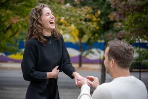 A joyful proposal moment captured outdoors with autumn foliage in the background.