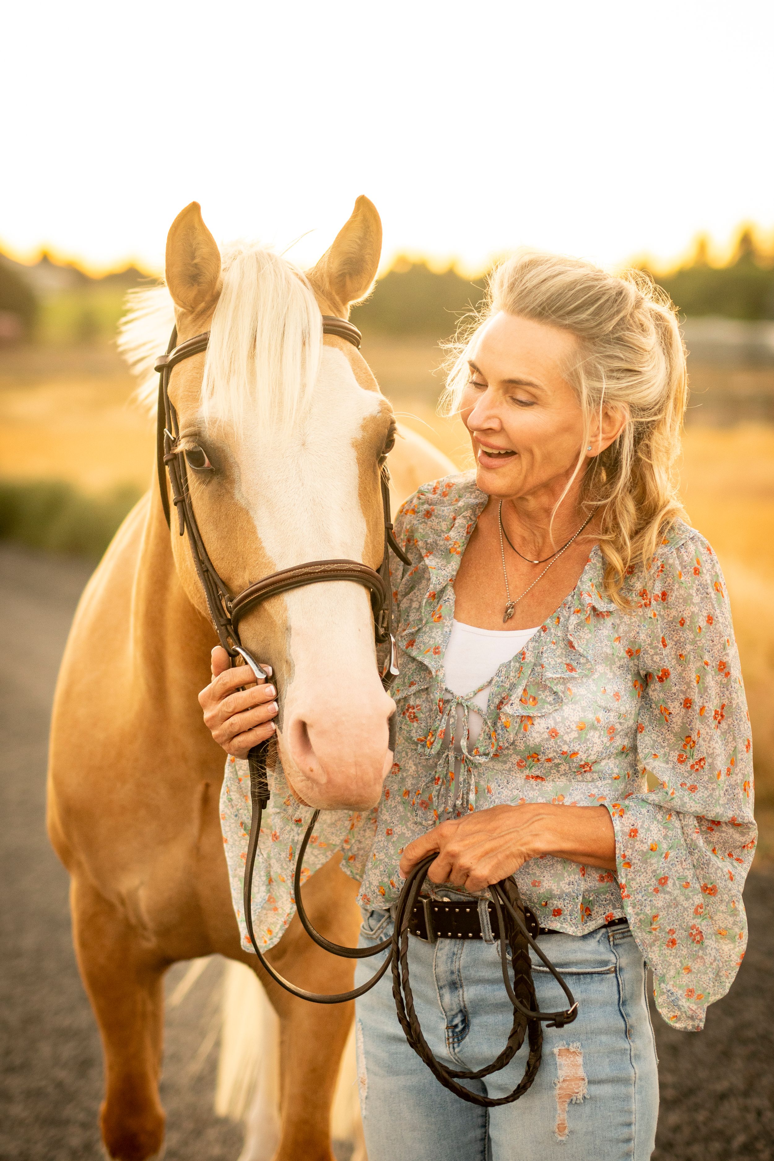 Palomino horse and owner share affectionate moment in warm evening light.