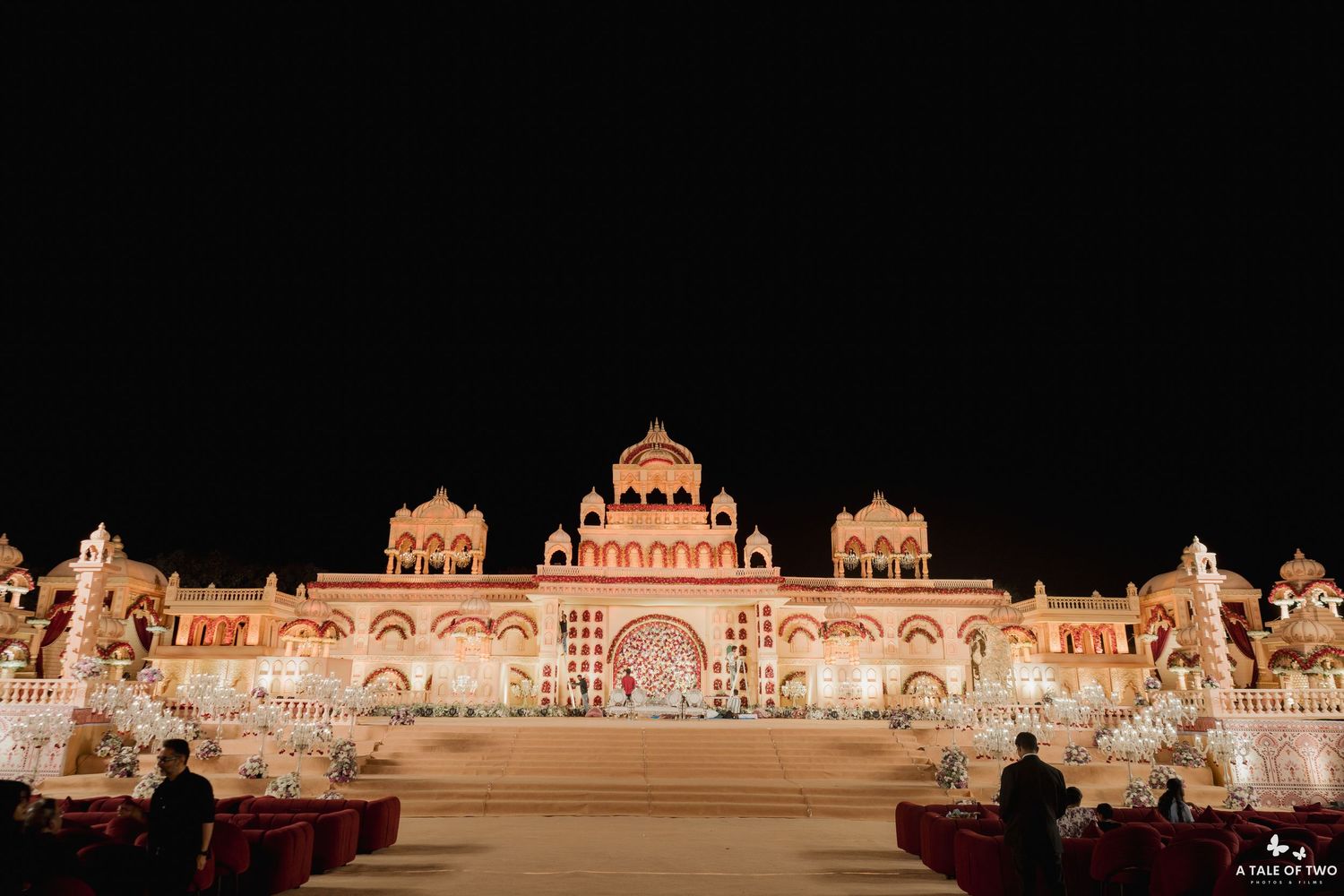 Illuminated grand Indian palace wedding venue glowing at night with ornate architecture and festive lights.