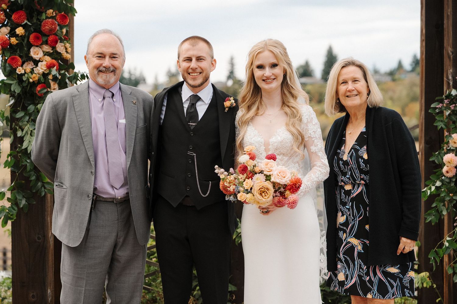 Wedding party poses together outdoors with vibrant autumn floral arrangements and decorations.