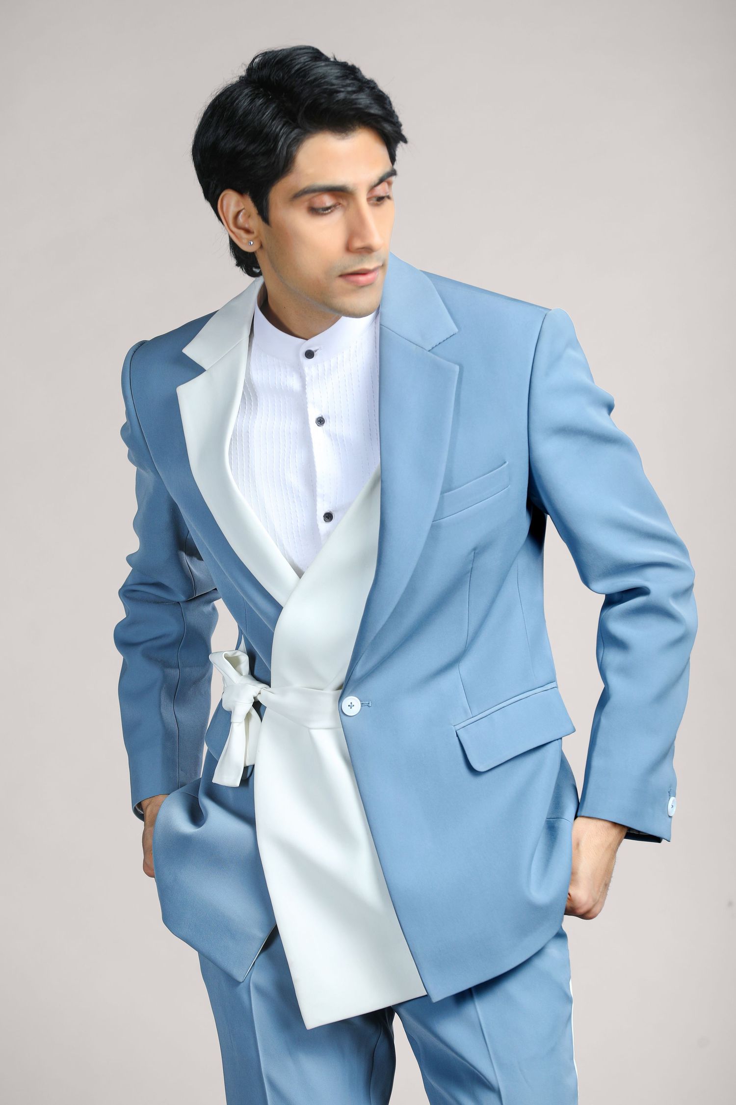 Fashion model wearing a light blue suit jacket with white dress shirt in multiple poses against a gray studio background.