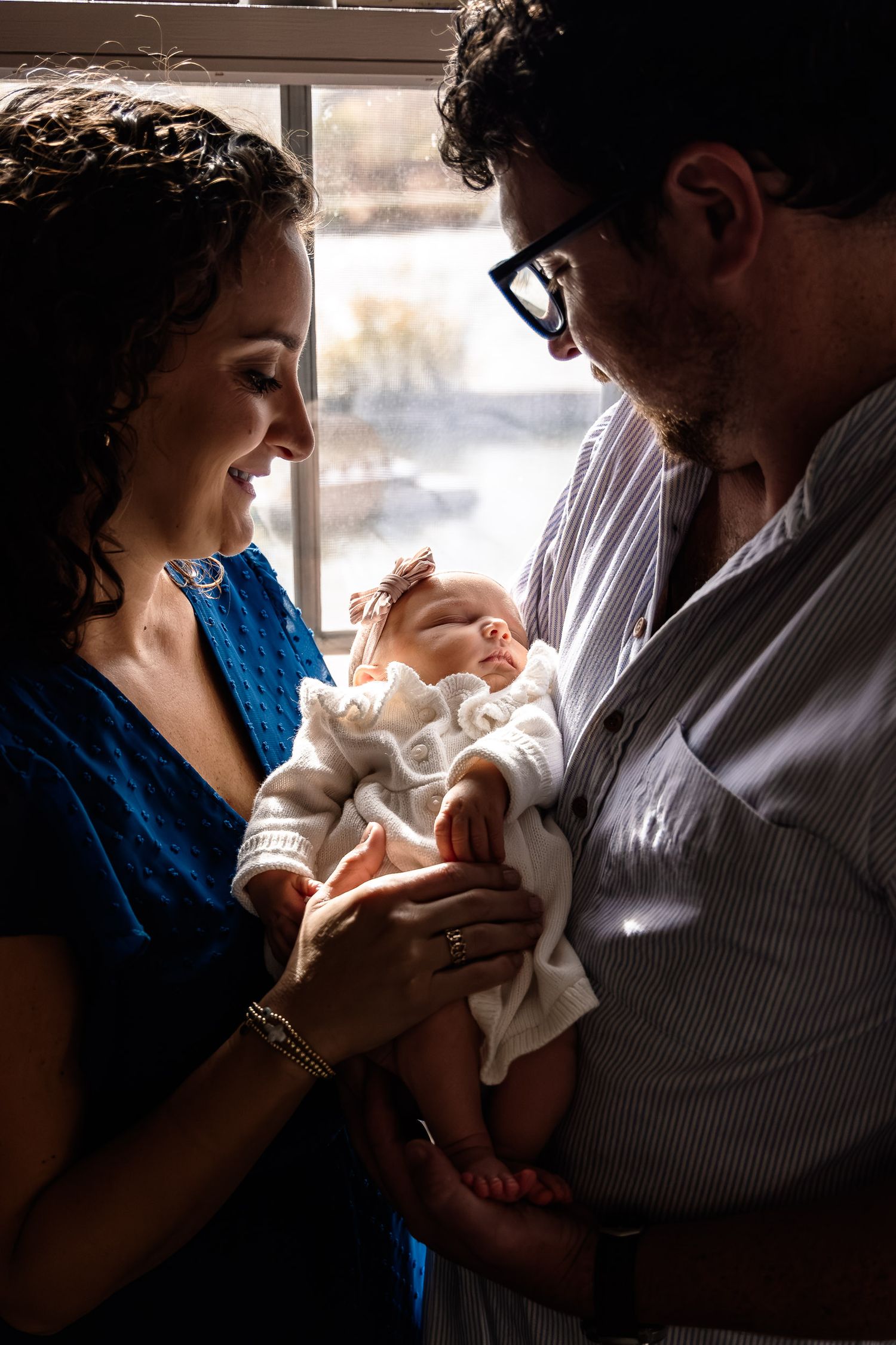Parents share tender moments with their newborn baby in a series of intimate backlit photographs.