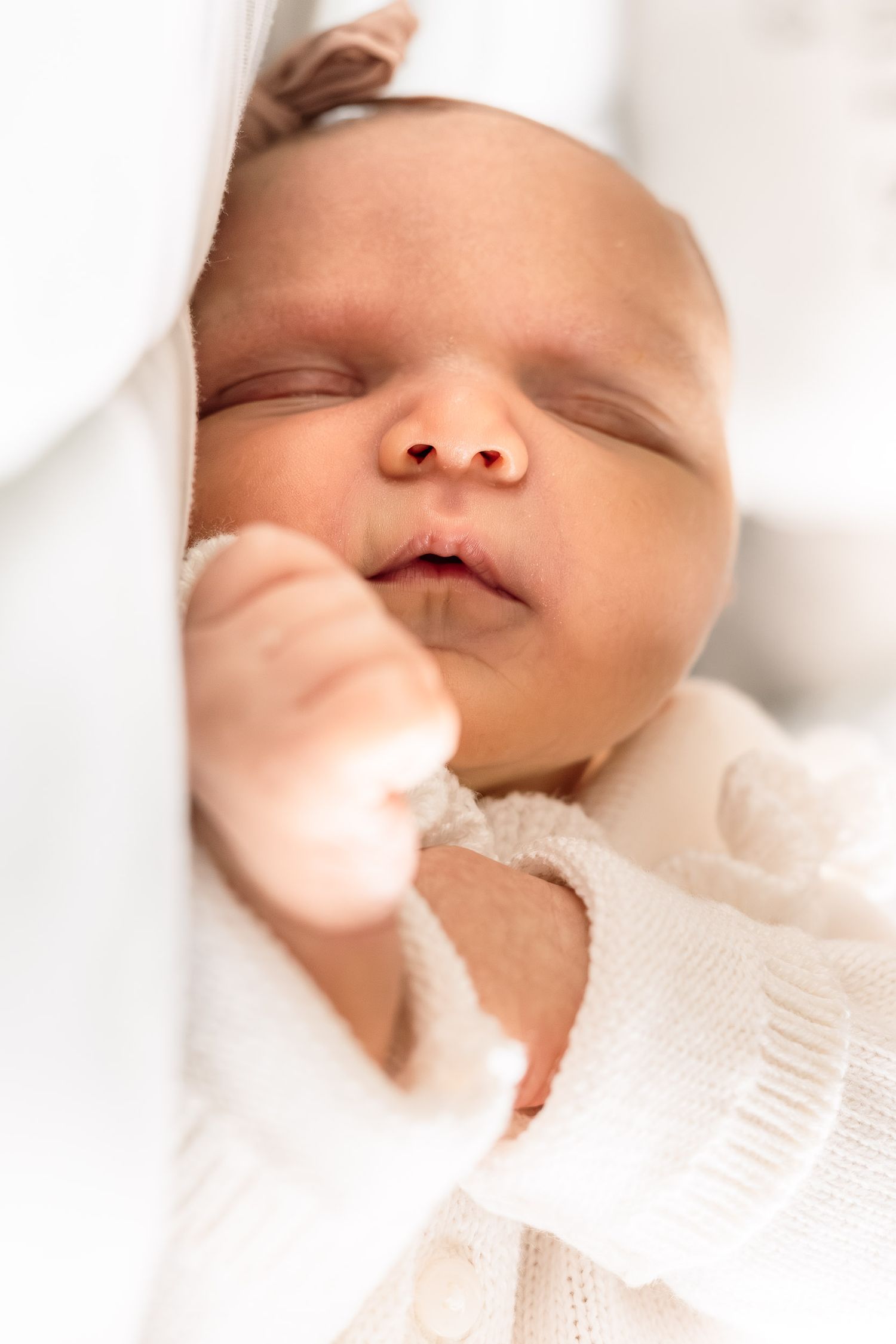 Close up of peaceful sleeping baby in soft white knit clothing.