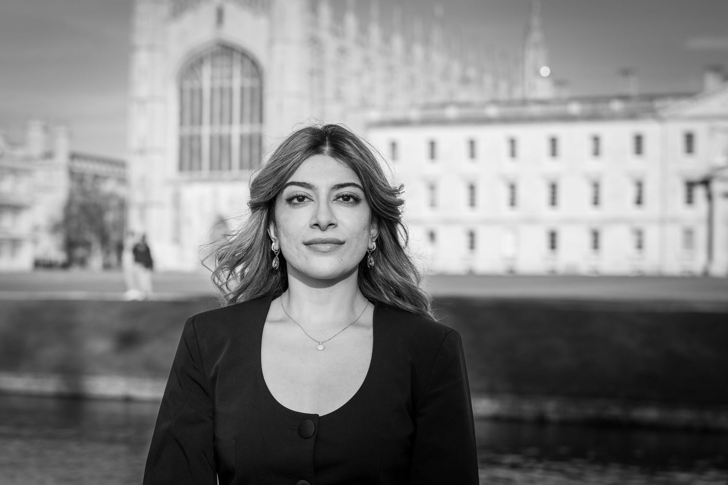 Black and white portrait of someone in dark attire standing in front of a historic Gothic building with spires.