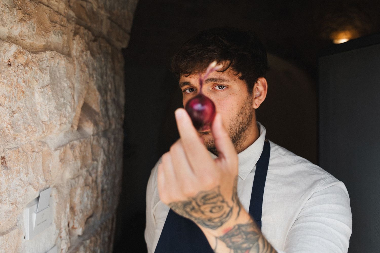 Porträtt av kock som håller upp en rödlök. Fotograferad i italien av Gabriel Alenius