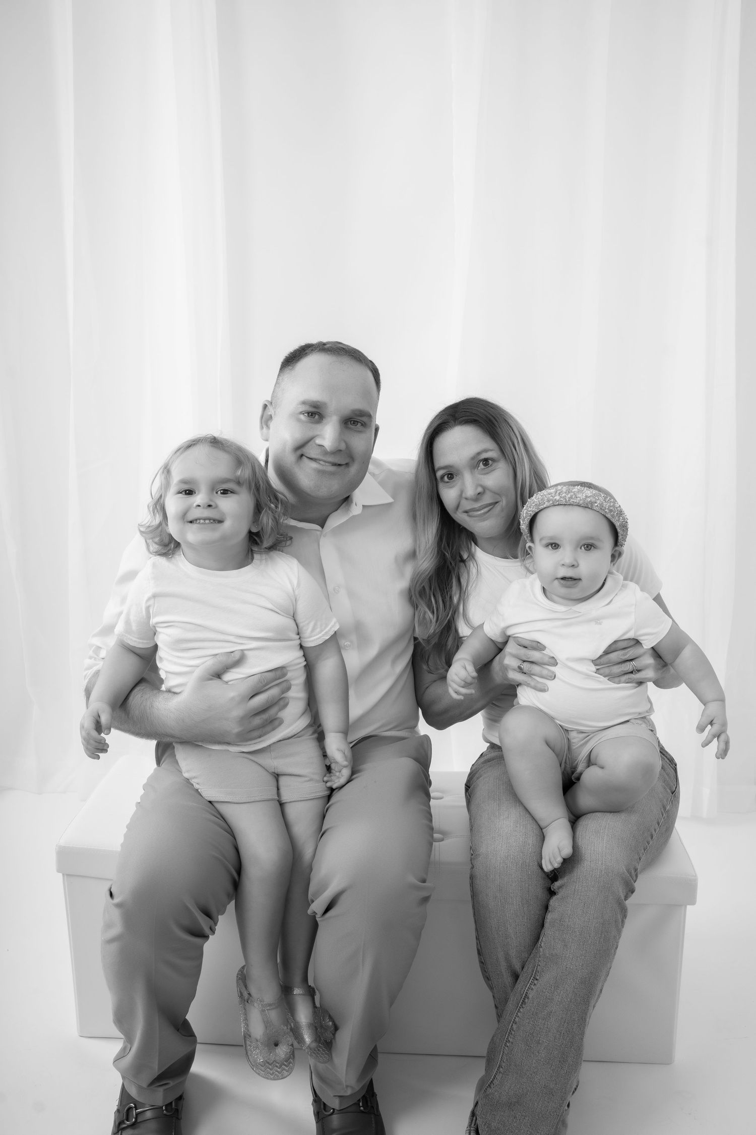 A family poses together on a white backdrop. The photo is in black and white.