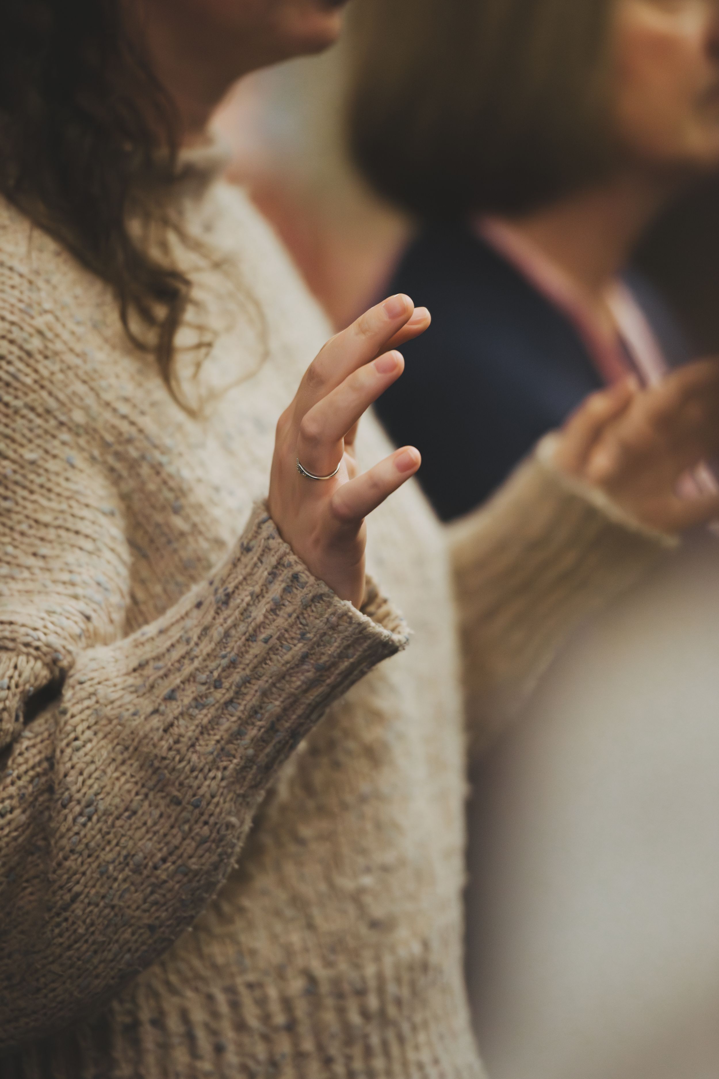Close-up sequence of hands gesturing in a beige knit sweater against a blurred background.