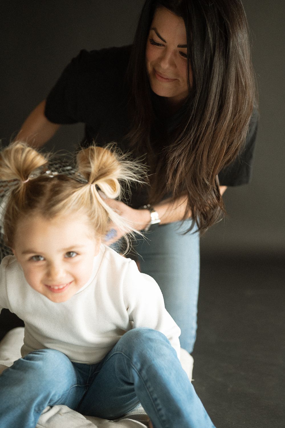 A candid moment of playful interaction between parent and child sitting on the floor in casual clothing.