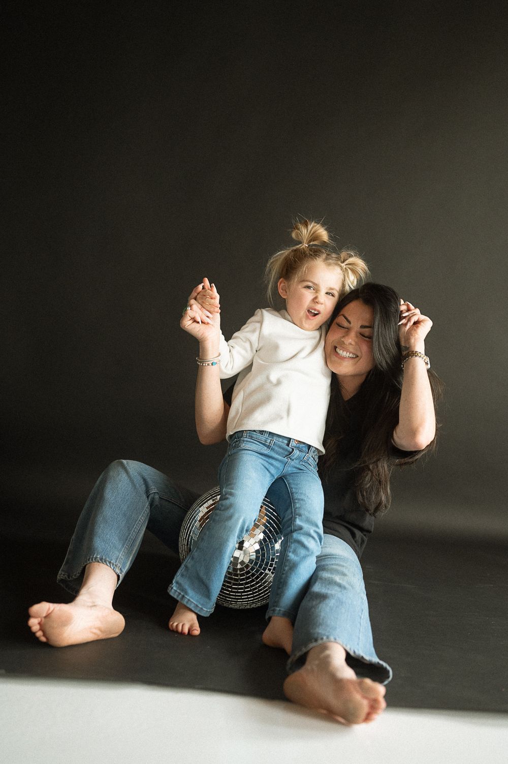 A series of intimate black and white photos showing tender moments between parent and child on a dark floor.