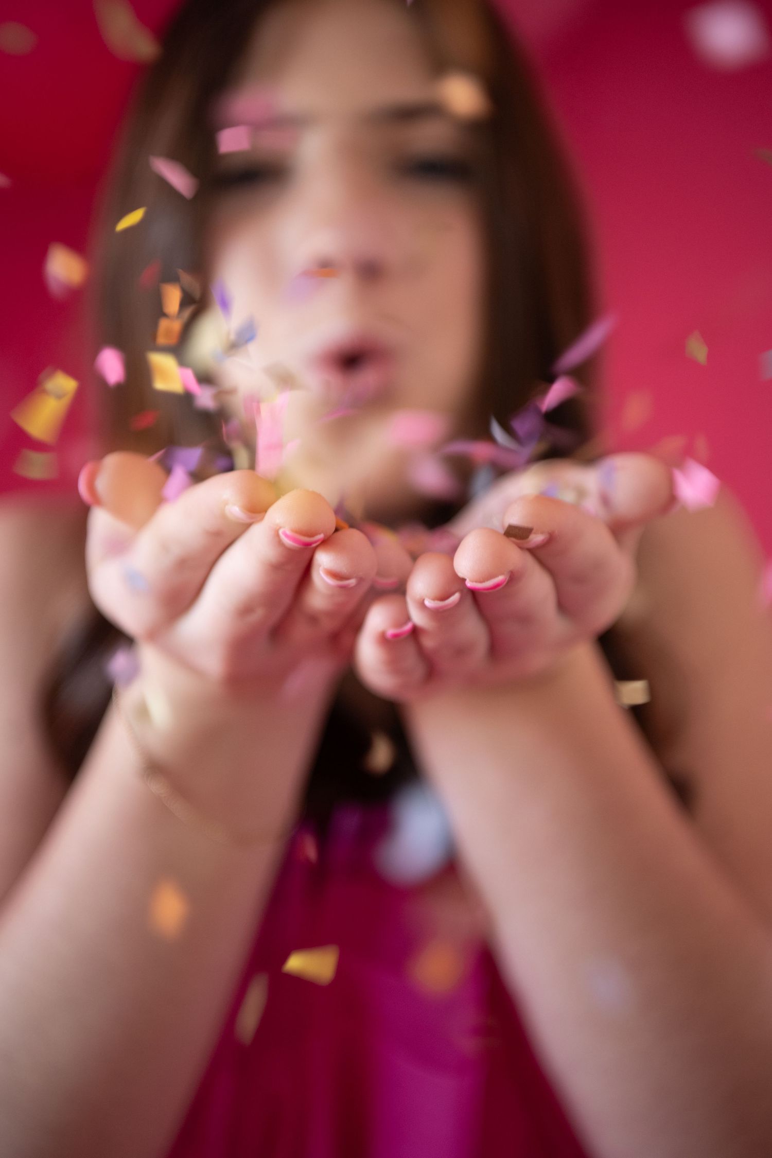 Someone blowing gold confetti against a vibrant red background in a celebratory sequence of photos.