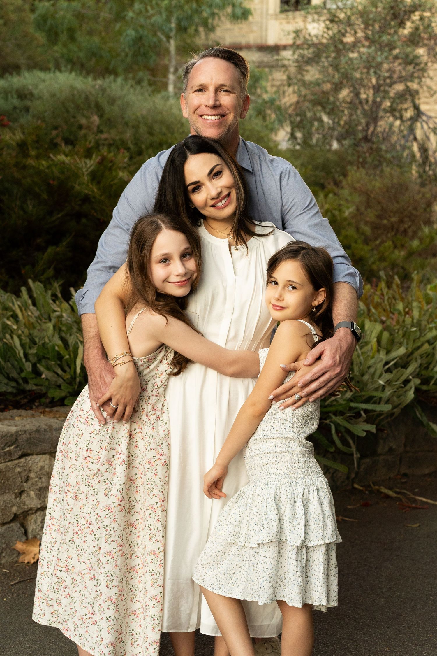 A father, mother and two children in an embrace outdoors during a Perth family photography session