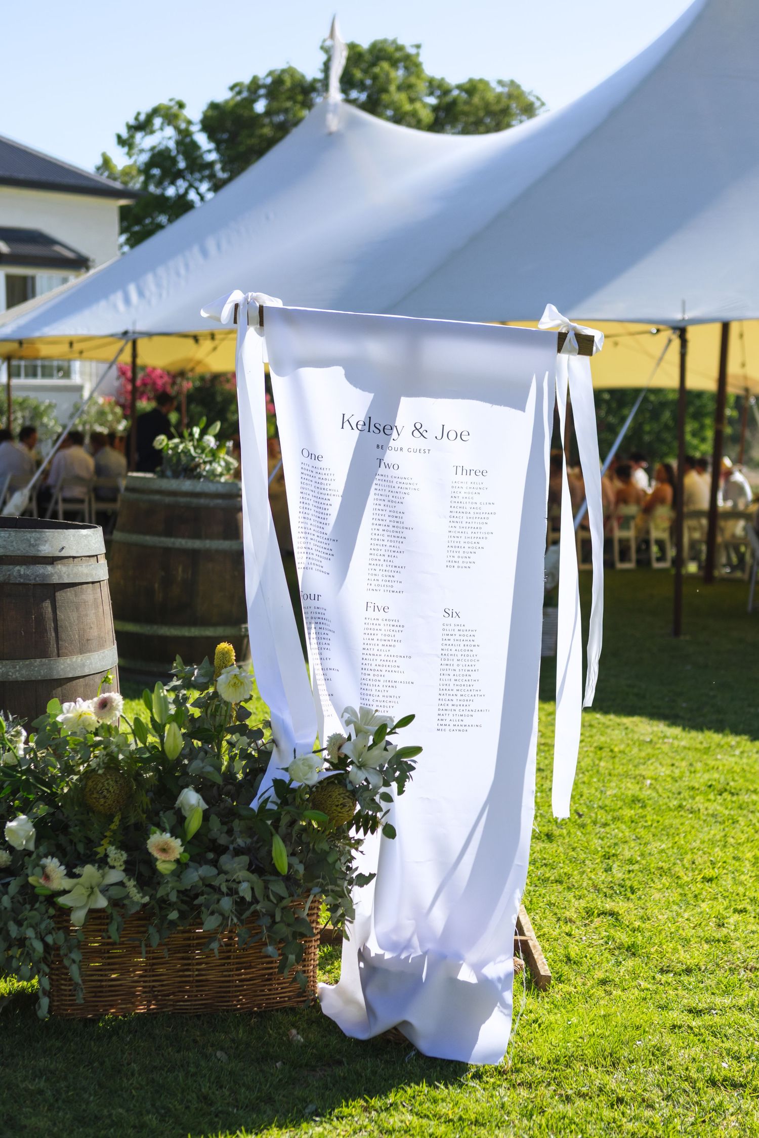 White linen sign with table placings outside marquee at country wedding