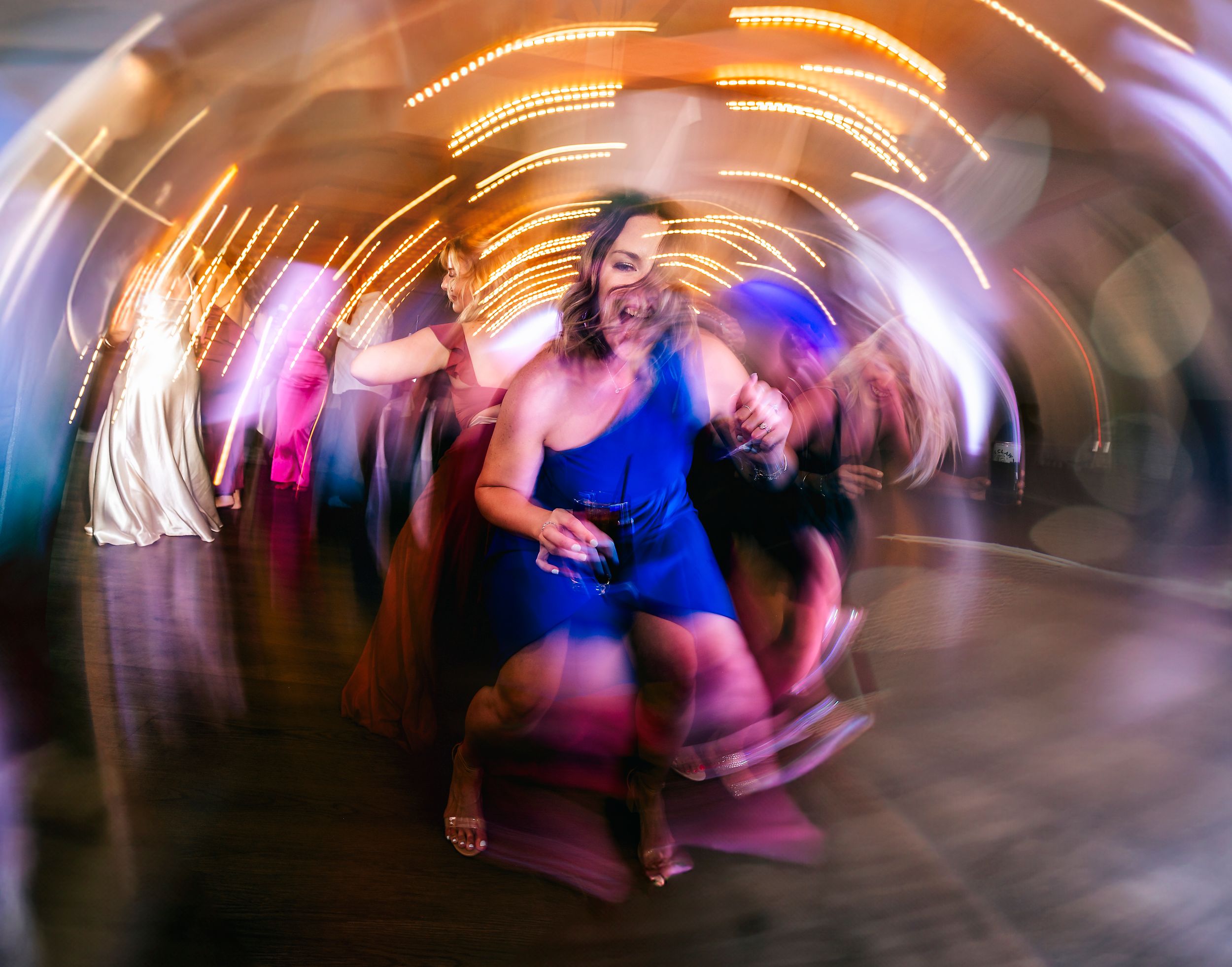 Creative long exposure photo of dancers creating light trails in blue and pink.