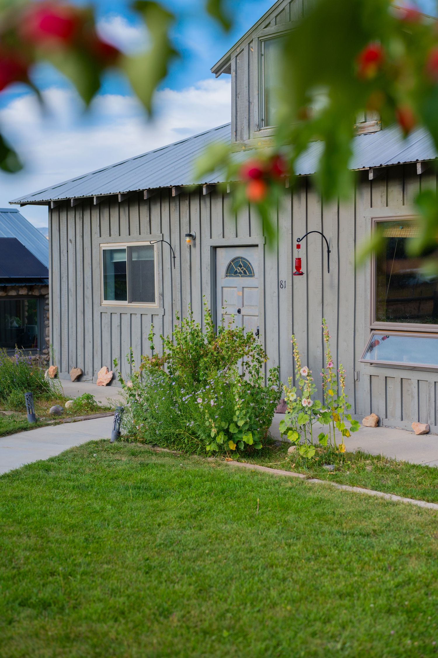 White exterior walls of a modern building with red flowers and green lawn in the foreground.