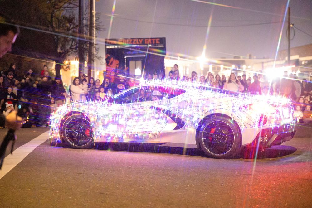 Illuminated holiday parade float decorated with colorful lights moving through a nighttime street.