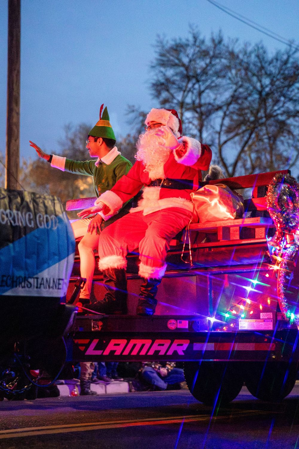 Festive float with inflatable Santa Claus figures illuminated by red and blue lights at night.