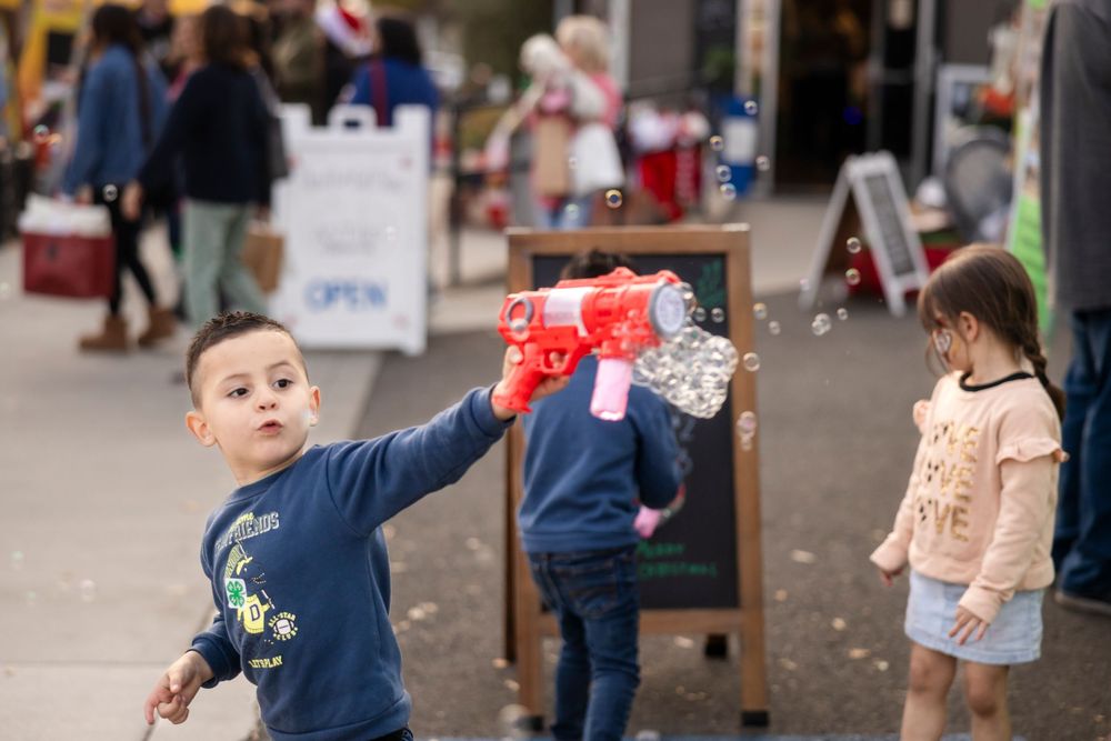 Children play with bubbles and engage in outdoor activities at a community event.