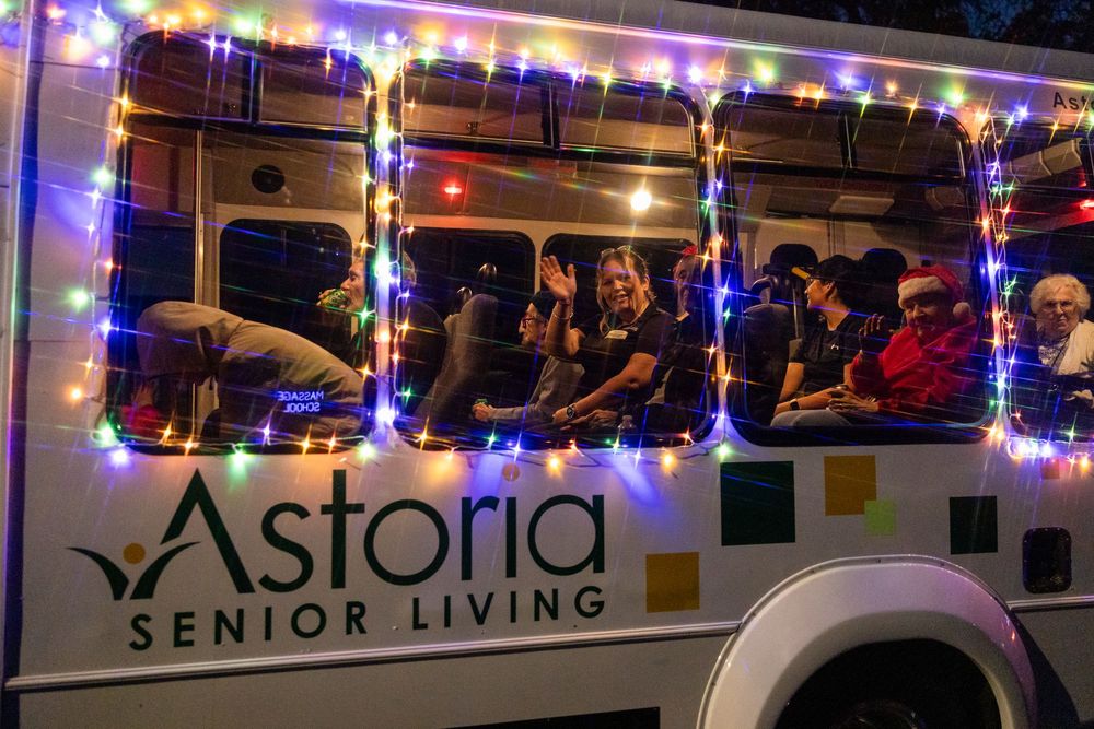 Bus decorated with bright blue and white LED lights displaying Astoria Senior Living signage.