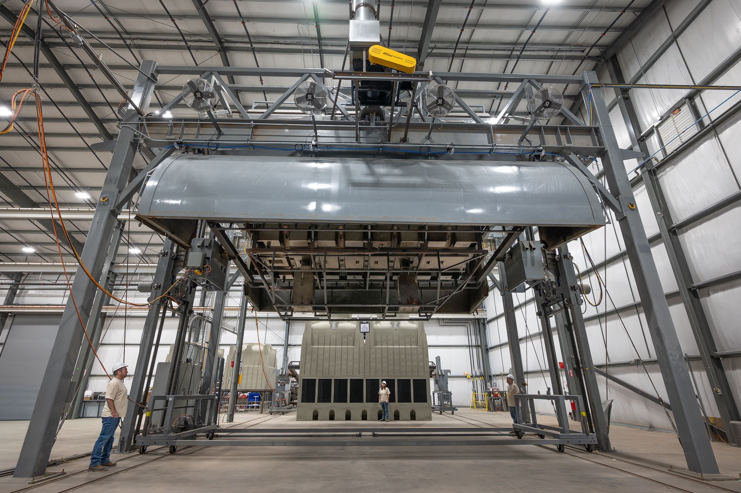 Industrial warehouse interior with metal framework and overhead lighting showing multiple connected sections.