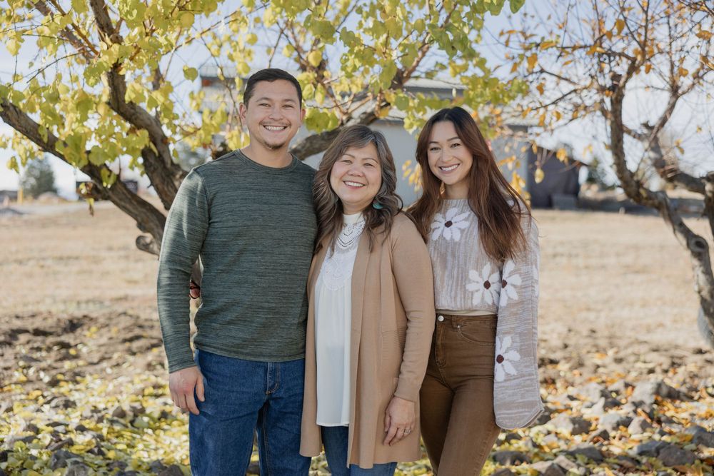 Family group poses together outdoors in coordinated fall outfits under yellow autumn leaves.