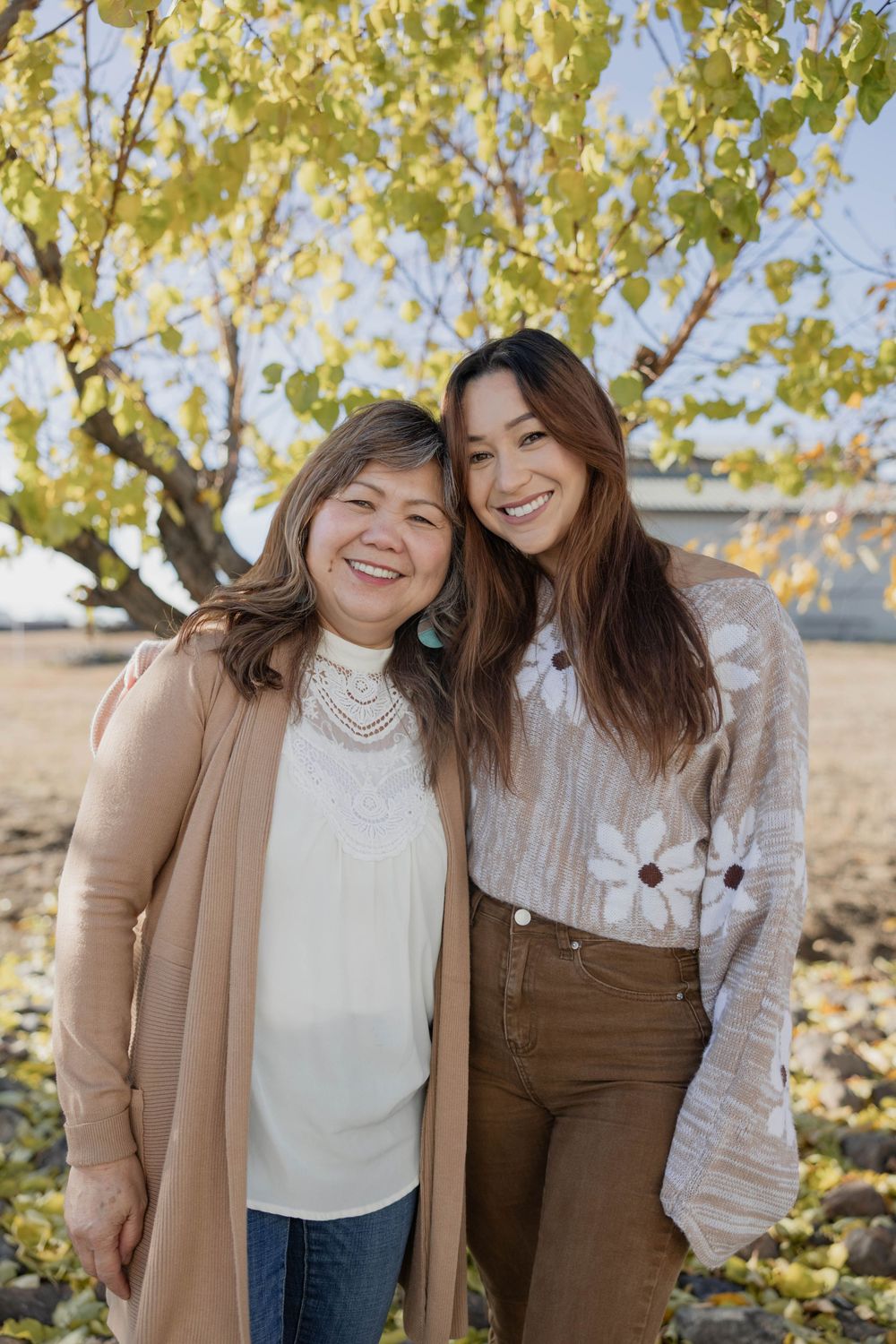 Two people share joyful moments during fall photoshoot with yellow leaves in background.