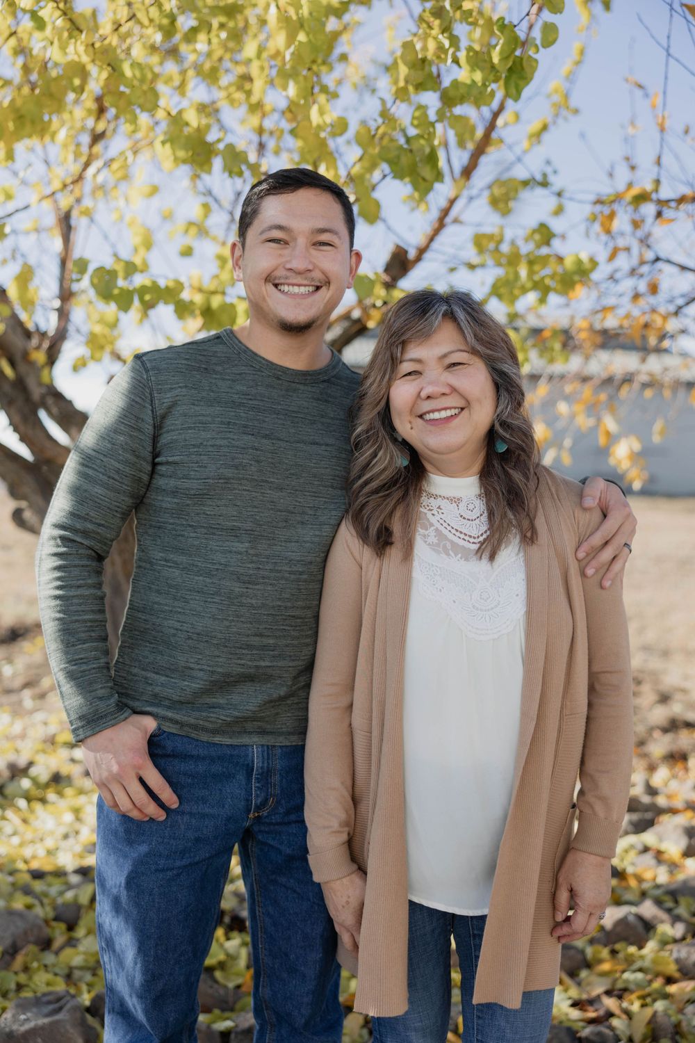 Candid outdoor portrait of pair in casual fall attire against autumn foliage.