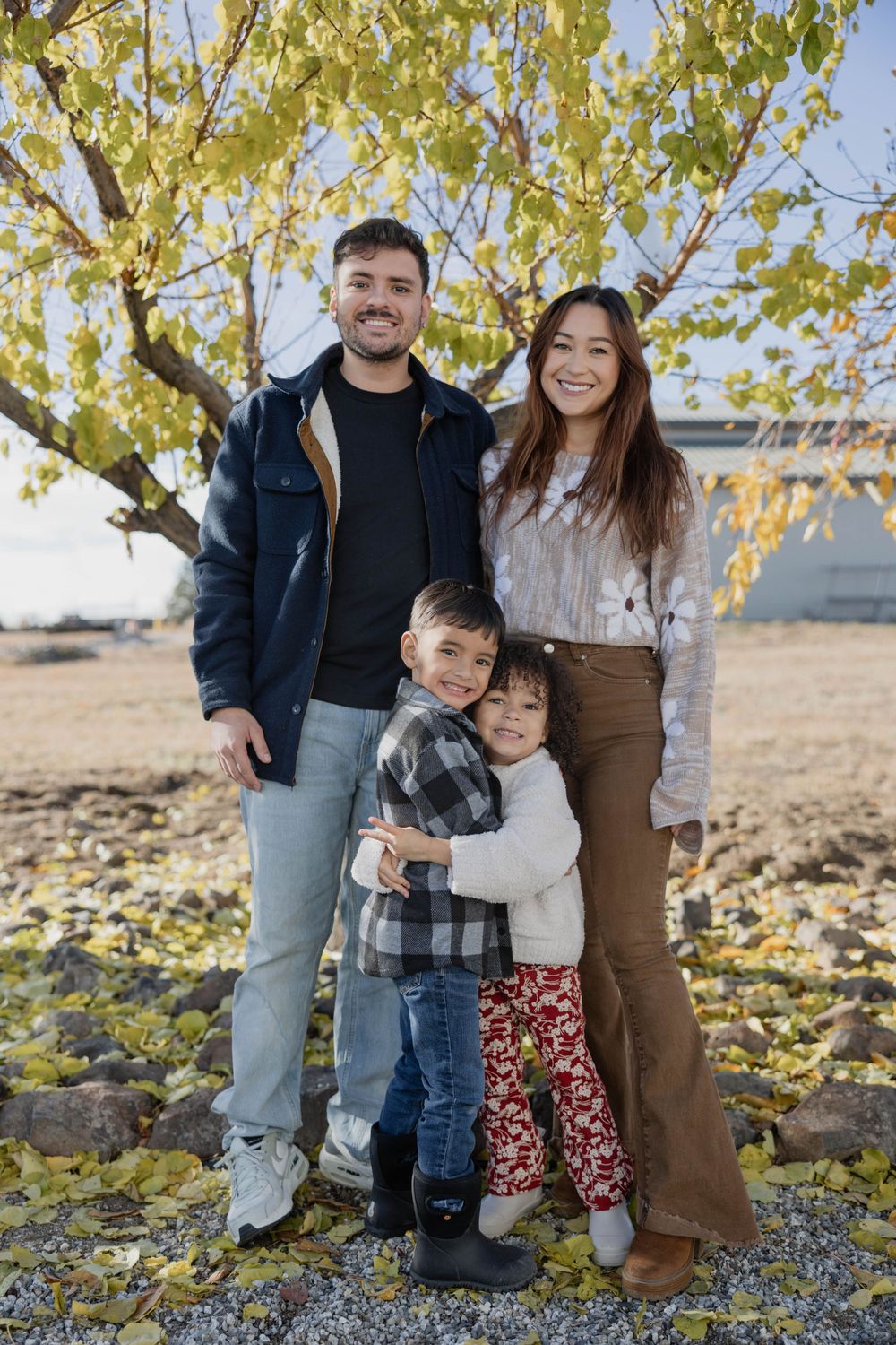 Family group photo session outdoors with autumn leaves and natural scenery.