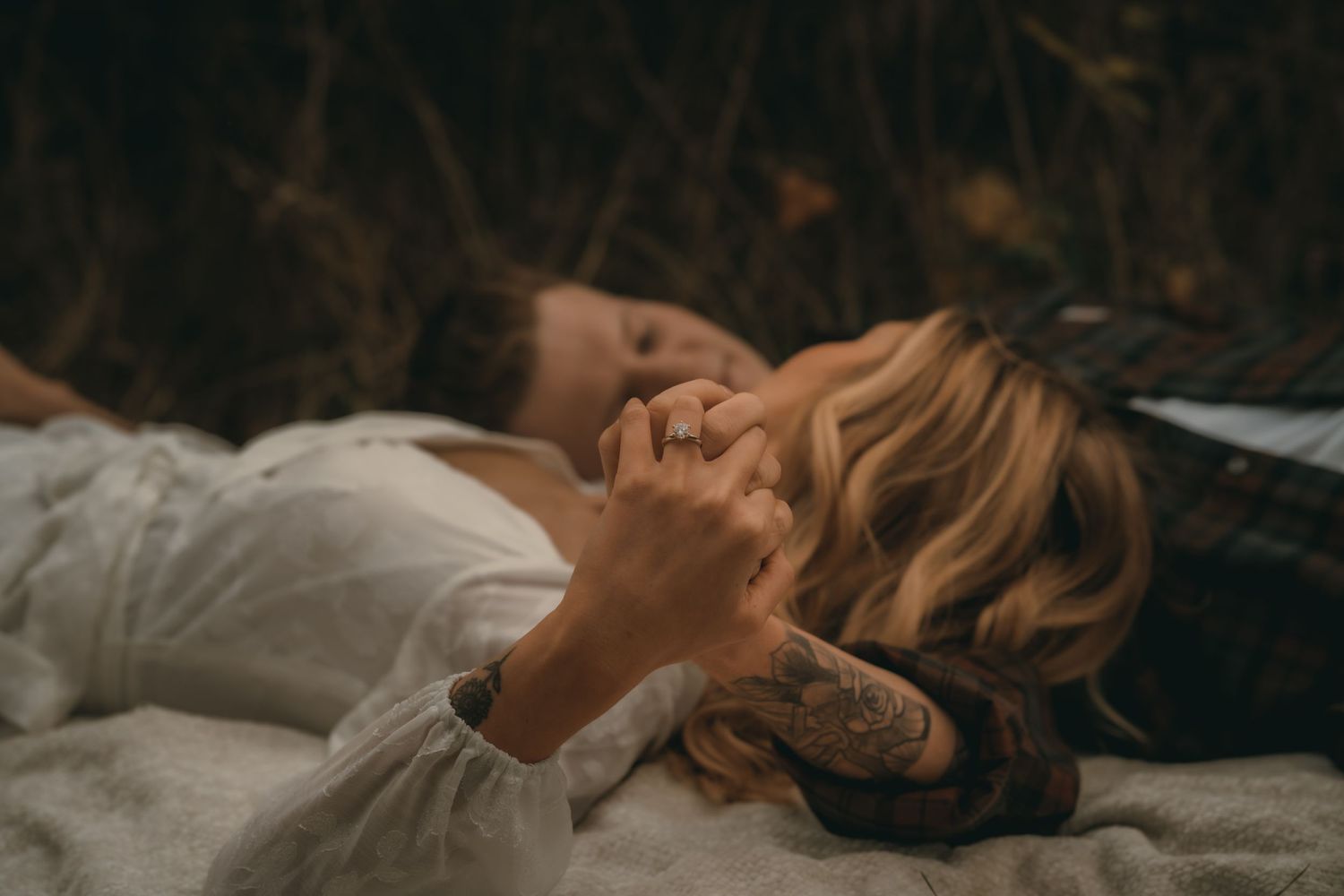 Couple lying down together in a romantic outdoor setting at dusk.